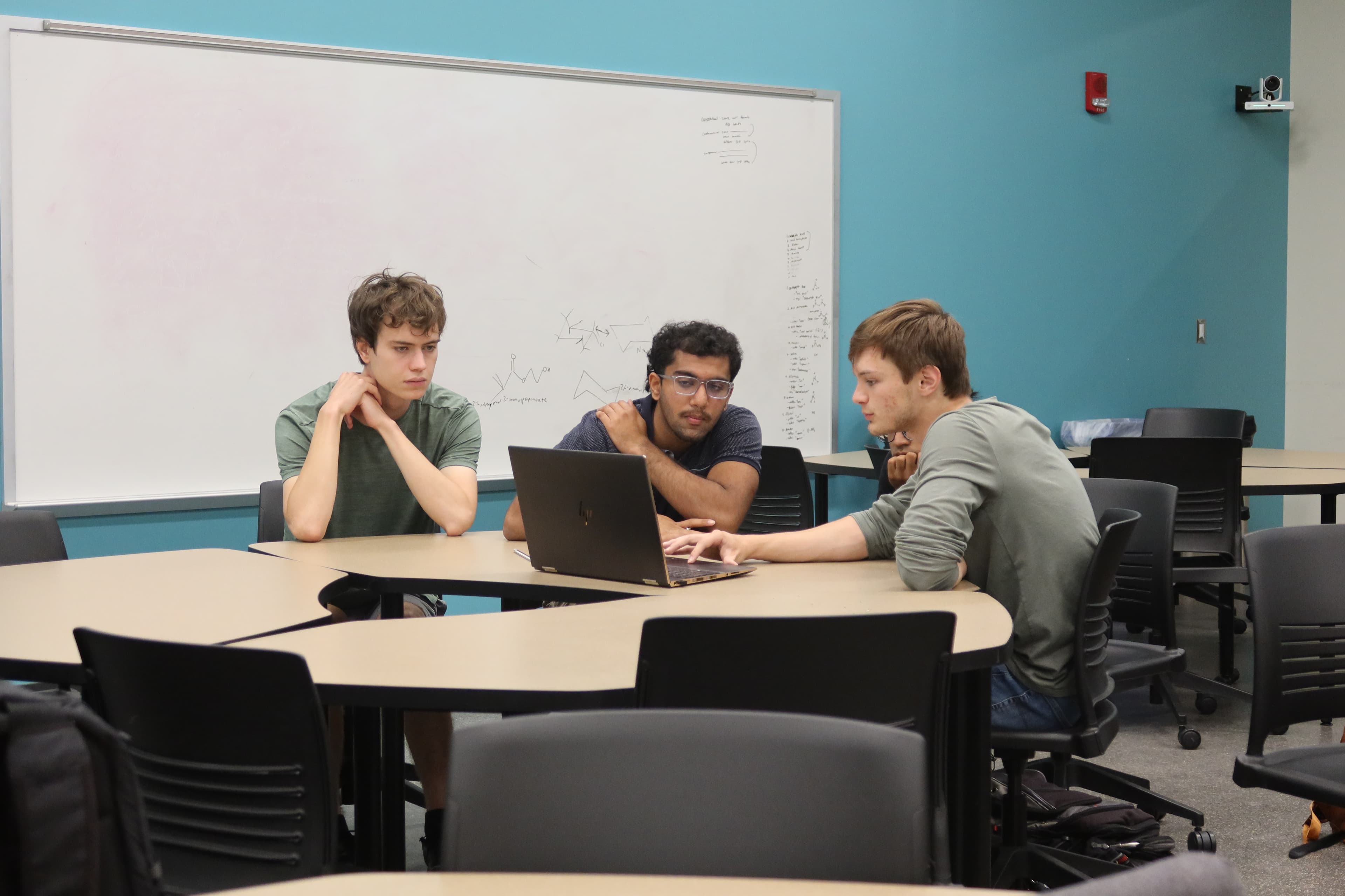 Three student founders reviewing work together on a laptop